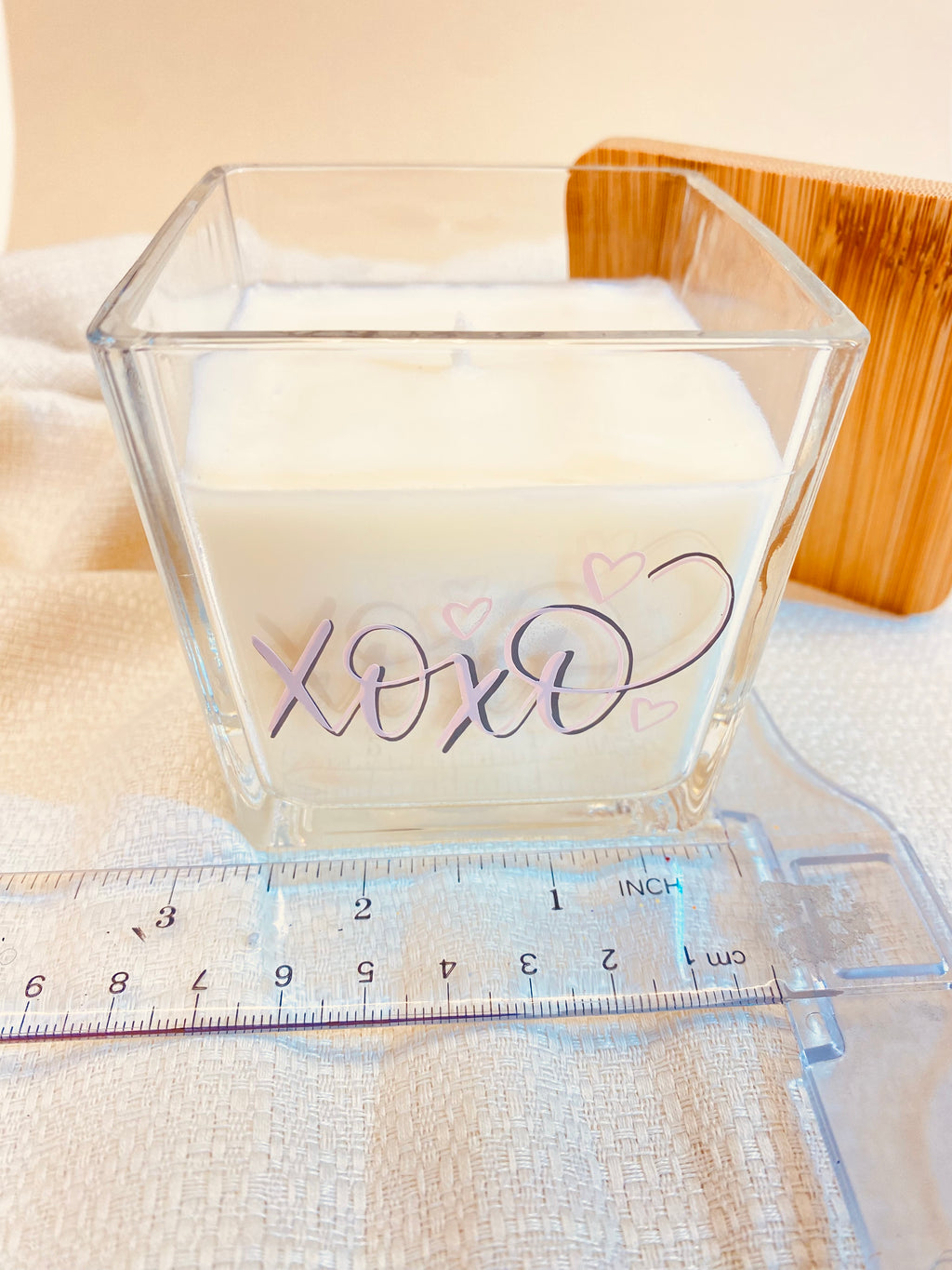 Natural Soy Wax Candle 9oz Customizable in a clear glass vessel with rose-toned XOXO script and natural wood lid.