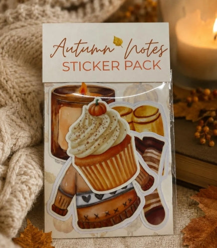 An 'Autumn Notes Sticker Pack' featuring illustrated autumn-themed stickers like a cupcake, pumpkin, cookies, and a sweater, shown in its packaging with a cozy fall background including a knitted blanket and a lit candle.