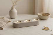 Elegant concrete tealight candle holder with three lit candles, enhancing home decor on a marble table.