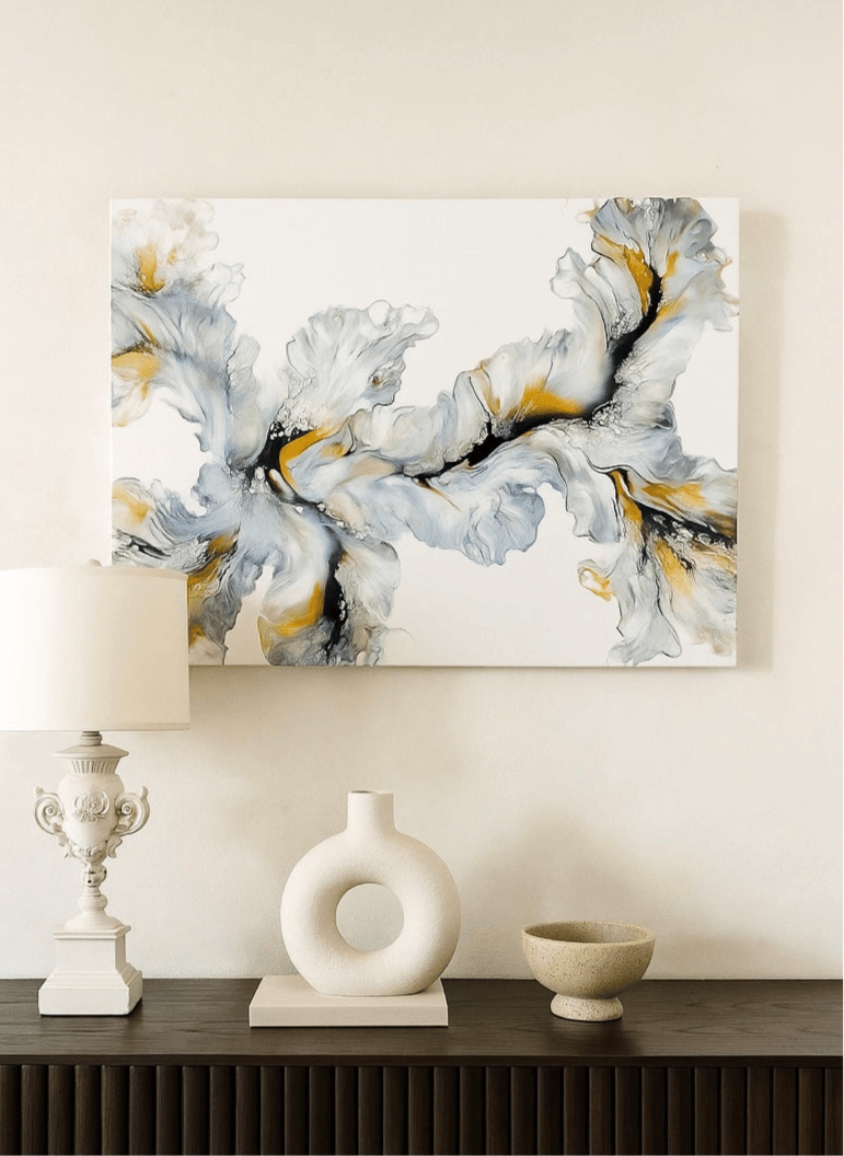 Abstract art piece on a wall above a console table with decorative items.