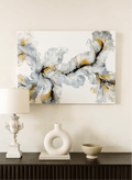 Abstract art piece on a wall above a console table with decorative items.